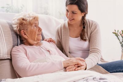 Pflegefachkraft betreut alte kranke Frau im Krankenbett Zuhause