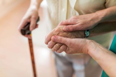 Pflegefachkraft hilft einer älteren Patientin und hält Ihre Hand